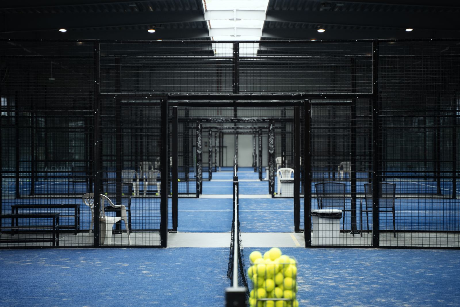 Indoor padel courts with a ball basket courtside