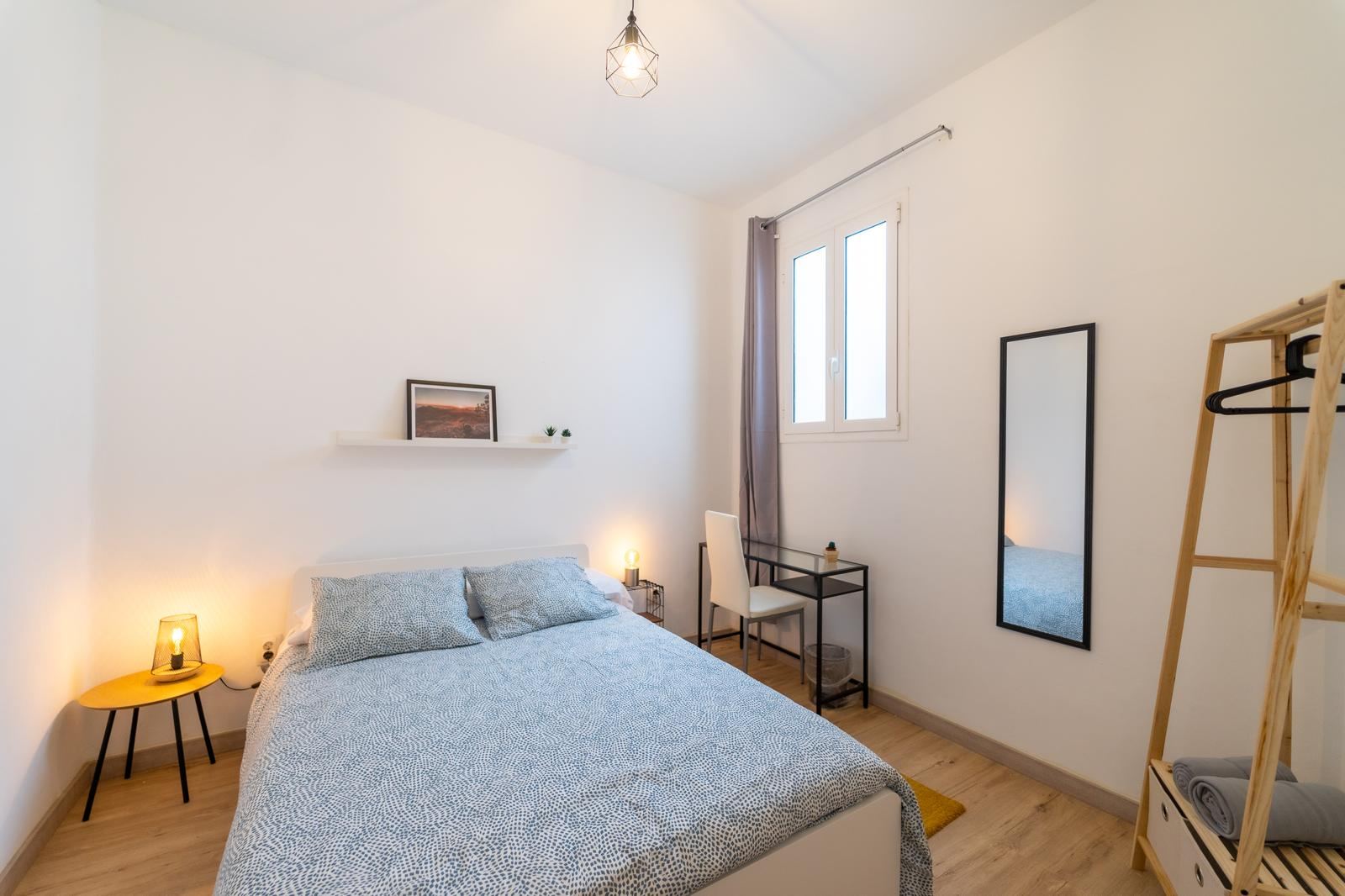 Bedroom with double bed, desk and clothes rack